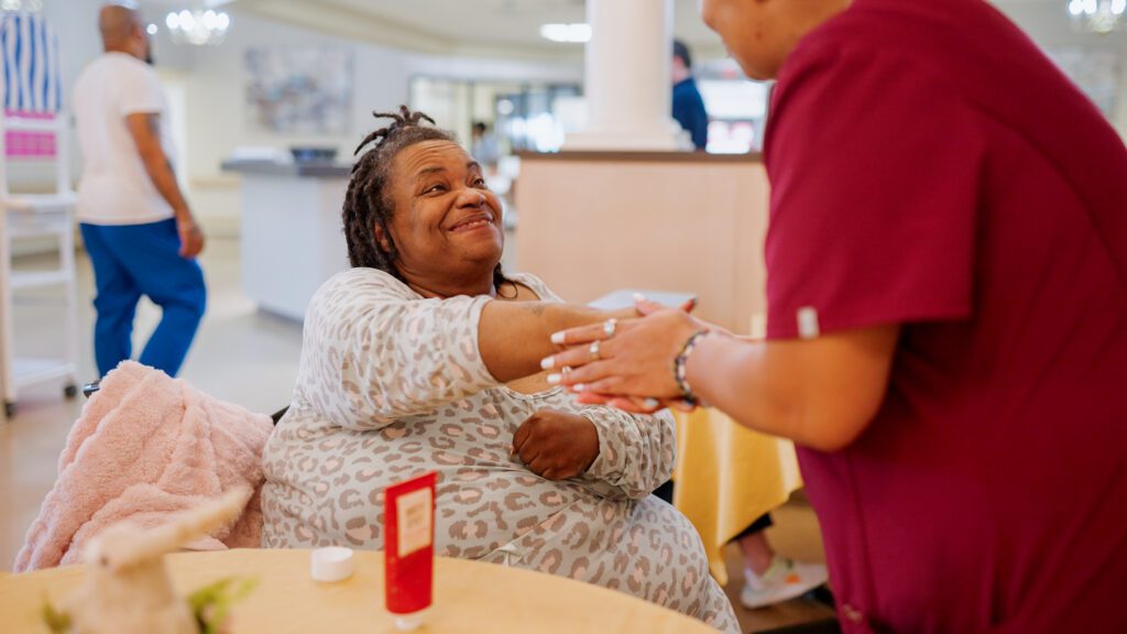 a nurse holding hands with a resident at a skilled nursing facility