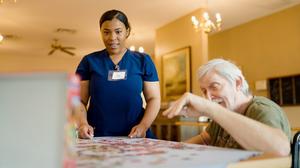 A man and nurse doing a puzzle together at a skilled nursing facility