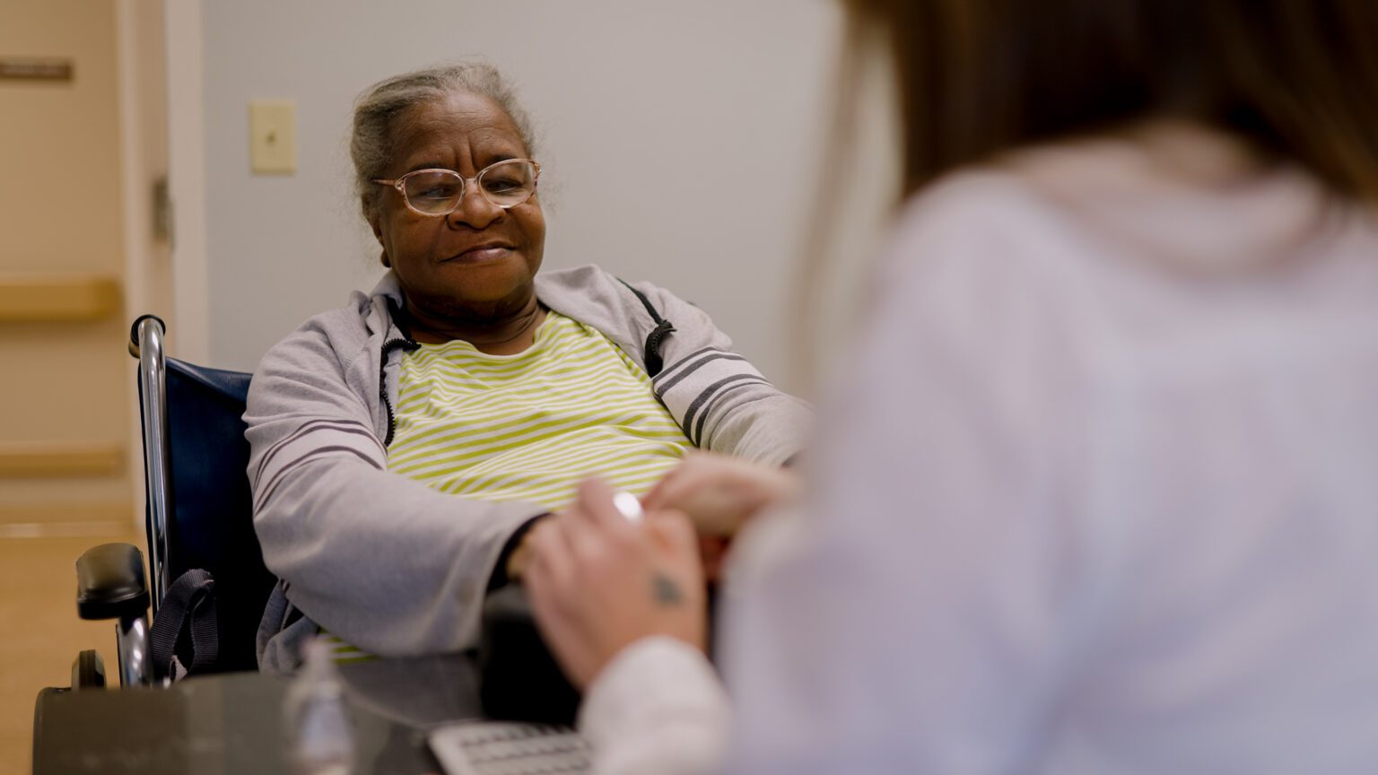 A woman gets her nails painted by a stylist at a skilled nursing facility