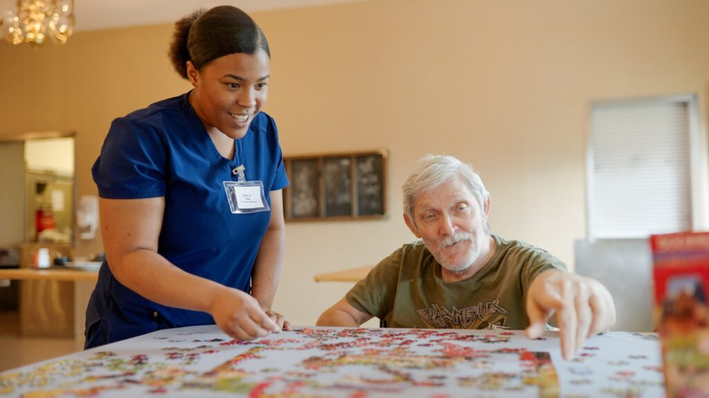 A nurse helps a long term care resident with a puzzle